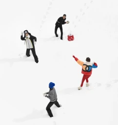 Aerial view of four models in winter ski apparel throwing snowballs on a snowy field for Chanel Coco Neige 2026