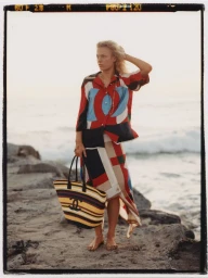 Model Liva Borre standing on a rocky beach holding a striped tote bag in a fashion editorial for InStyle Mexico by Alex Feggi.