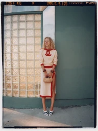 Model Liva Borre wearing a cream and red knit outfit leaning against a building exterior for InStyle Mexico