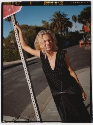 Model Liva Borre leaning on a street sign in a black pinstripe dress for InStyle Mexico photographed by Alex Feggi