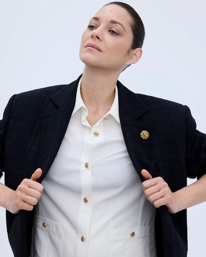 Marion Cotillard wearing a black blazer and white collared shirt against a plain light background for Elle France