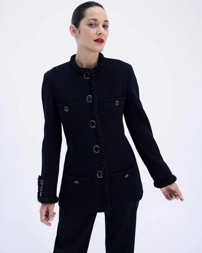 Marion Cotillard wearing a black buttoned jacket against a plain white studio background for Elle France.
