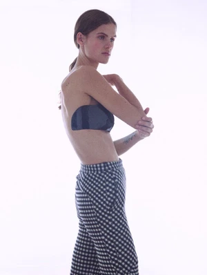 Model Lucia Richardson in a black strapless top and checked trousers against white seamless background