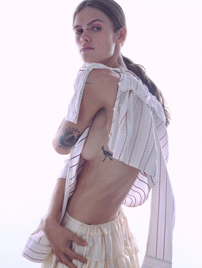 Model wearing a white striped top and cream skirt against a bright white background for Household by Crosscurrent