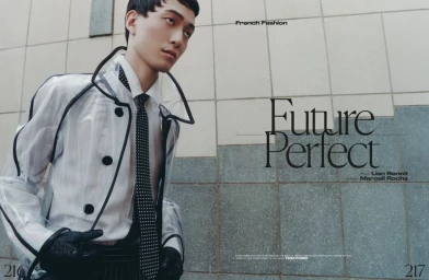 Model in clear vinyl coat with black trim wearing a patterned tie and dark gloves against a tiled wall