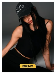 Amelia Gray wearing a black tank top and a dark baseball cap against a grey studio backdrop for DKNY Fall 26 Edit.