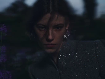 Close-up portrait of a model in a dark textured jacket under dim twilight light for Dior Giverny by night