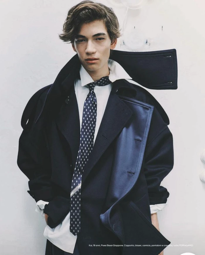 Young man wearing a dark coat, white shirt, and patterned tie against a plain white background for Esquire Italia.