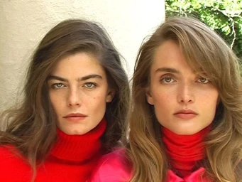 Two female models with long hair wearing vibrant red turtleneck sweaters in a close-up portrait for Harpers Bazaar US.