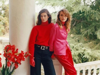 Two female models posing near a classical white column with red flowers for Harper's Bazaar U.S.