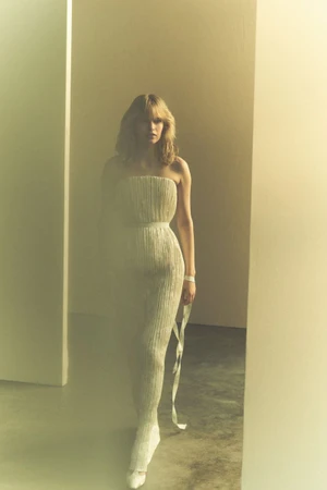 Model Aivita Muze in a textured white strapless gown walking through architectural pillars for Danielle Frankel.