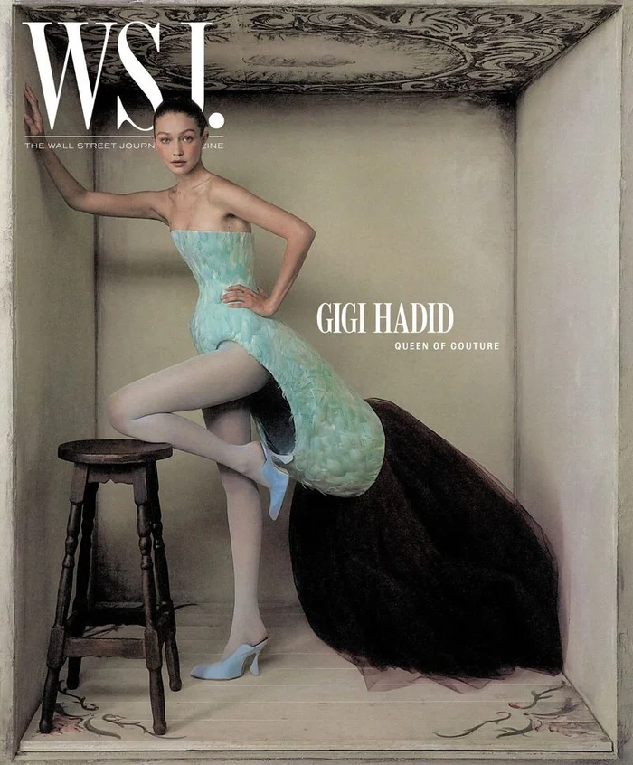Model Gigi Hadid posing inside a textured sculptural box set wearing a structured strapless mini dress and light blue mules