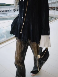 Model in black pleated blouse and textured trousers holding a quilted handbag for Dior Summer 2027 Show