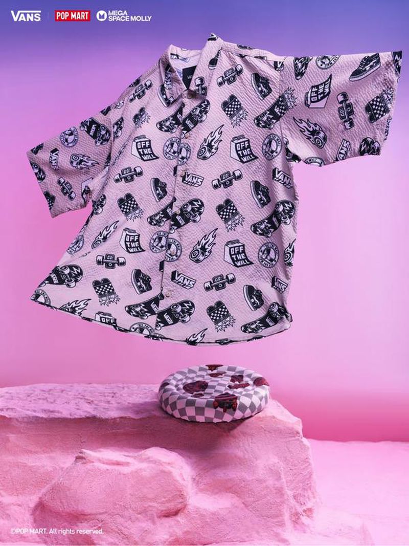 Pink Vans shirt with skateboard and logo designs floating above a pink platform, set against a graduated pink and violet background.