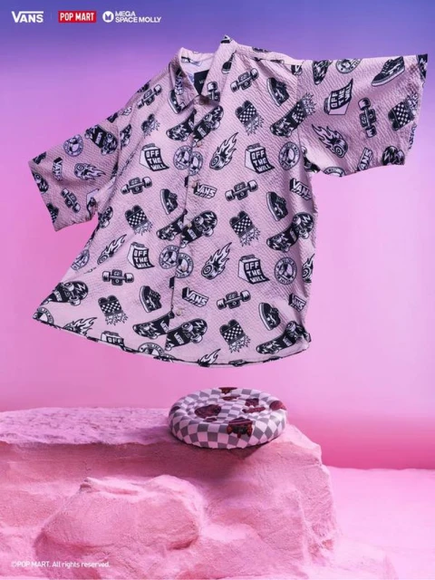 Pink Vans shirt with skateboard and logo designs floating above a pink platform, set against a graduated pink and violet background.