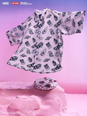 Light pink graphic short-sleeve button-up shirt floating above a sculpted pink surface with a checkered circular cushion.