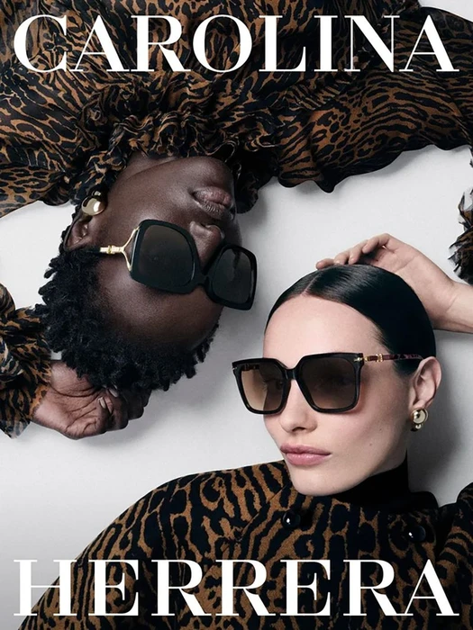 Two models wearing leopard print tops and black sunglasses against a white background for Carolina Herrera eyewear.