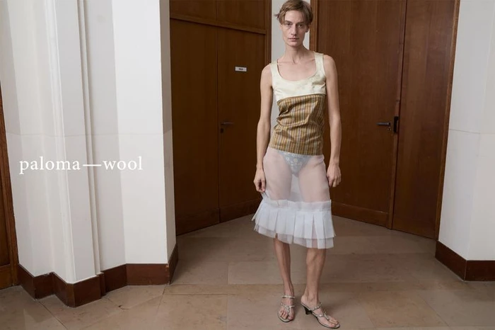 Model standing in a hallway wearing a sleeveless patterned top and a sheer skirt with ruffled hem