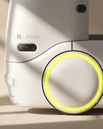 Close-up of the Rovex Rovi 01 white device featuring a glowing yellow circular ring light and camera lenses on a neutral surface.