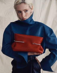 Model Summer Dirx in a blue high-neck top holding a red leather clutch for Saks