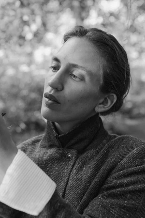 Black and white portrait of a woman wearing a textured tweed jacket outdoors with a blurred natural background