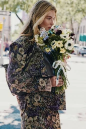 Grace Elizabeth holding a large bouquet of wildflowers wearing a floral jacquard jacket for Veronica Beard fall campaign