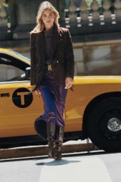 Grace Elizabeth walking in front of a yellow taxi wearing a brown fringe blazer and purple silk skirt
