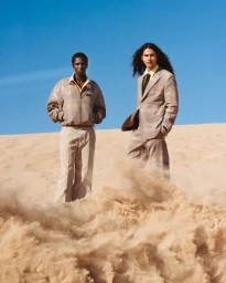 Two male models standing on a sandy dune against a blue sky for the Ocean Dunes project in At Large Magazine.