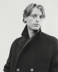 Portrait of young male model Colin Otto wearing a dark double-breasted coat for Le Figaro photographed by Valentin Hennequin