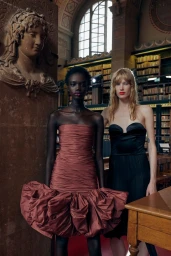 Two models posing in a historic library interior, wearing strapless ruched gowns designed by Alessandro Michele for WWD.