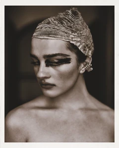 Portrait of a model wearing a textured patterned head covering and dark eye makeup with silver ear cuffs for SHADOWPLAY Magazine.