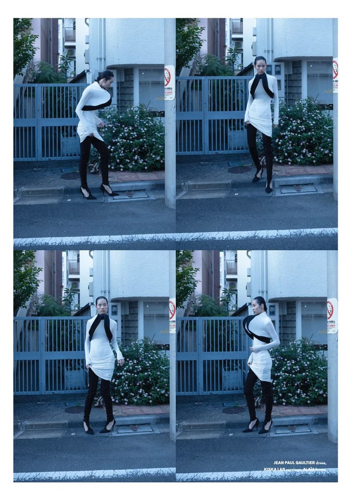 Model Song Ah Woo in a white dress and black leggings posing on an urban street for Exhibition Magazine