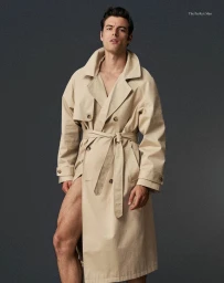 Male model in a beige belted trench coat against a dark grey textured background for The Perfect Man Magazine.