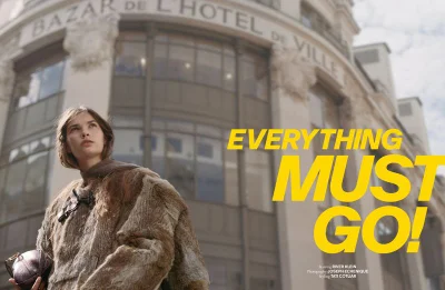 Model River Klein wearing a textured fur jacket holding a small handbag outside a classic stone building.