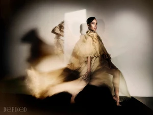 Kerry Washington seated in a layered sheer ruffled gown against a textured studio wall with multiple exposure motion blur effects