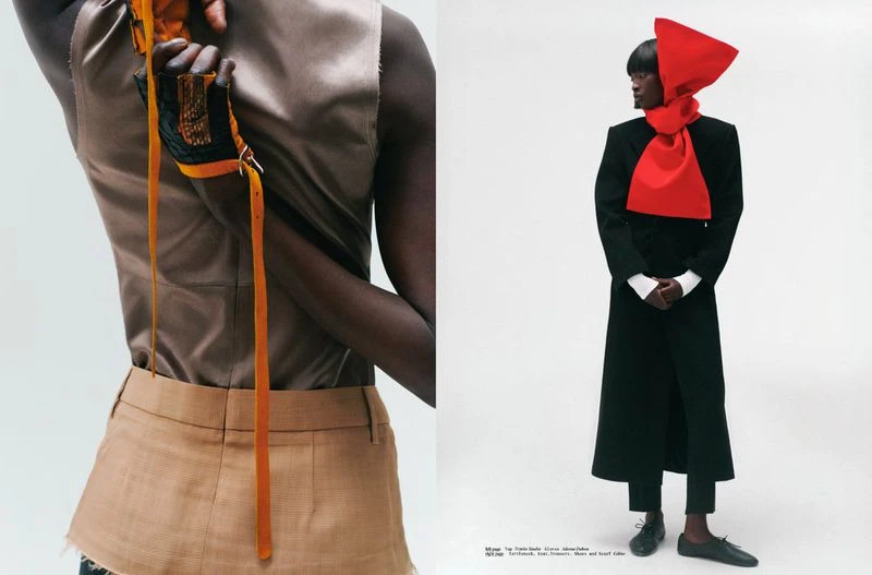 Model wearing a black coat with a sculptural bright red scarf against a plain white studio background.