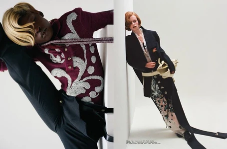 Two models posed against white structural walls wearing textured burgundy knitwear and a long black coat in a fashion editorial diptych.