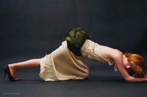Model with red hair kneeling on a dark floor in a champagne satin skirt and green faux fur piece, photographed by Zoe Natale Mannella.