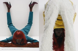 Model with red hair wearing teal trousers and dark heels posing upside down against a white background for magazinemagazine