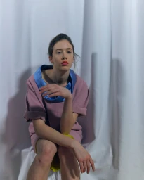 Model wearing a pink dress with a blue collar against a white backdrop