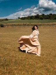 Woman in billowing cream gown running through a dry open field under a partly cloudy sky for Elle Bulgaria