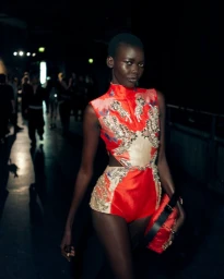 Model Achol Ayor backstage wearing an embellished red and gold outfit for Erdem SS27 captured by Fran Gomez de Villaboa