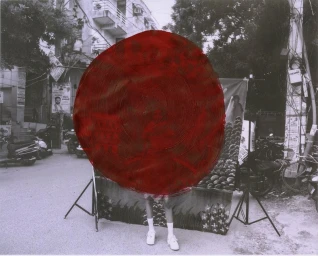 Black and white street photograph with a large painted red circular shape obscuring a person standing outdoors