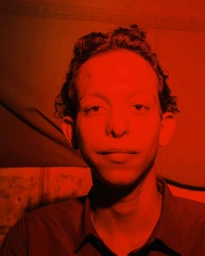 Portrait of a young person bathed in intense monochromatic red lighting with dark clothing