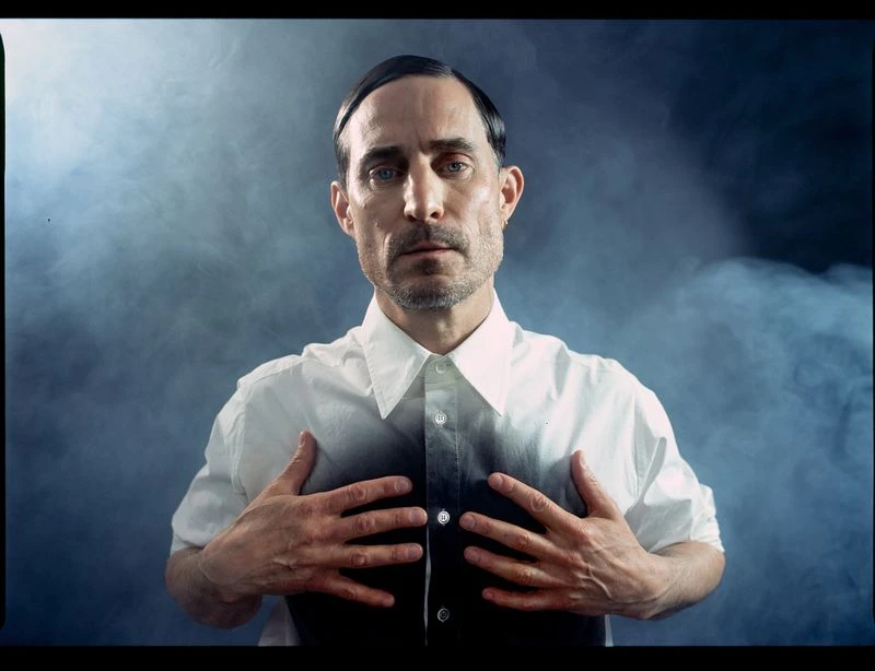 Portrait of Clemens Schick wearing a white button-down shirt against a smoky blue background for Sleek Magazine by Szymon Stepniak.