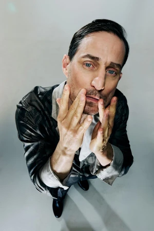 Actor Clemens Schick looking upward with hands near his face for Sleek Magazine, photographed by Szymon Stępniak.