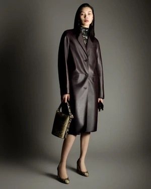 Model Bingbing Liu wearing a dark leather coat and holding a patterned handbag against a grey backdrop