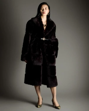 Model Bingbing Liu wearing a dark belted faux fur coat and patterned heels against a gradient grey studio backdrop.