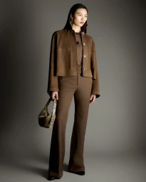 Model Bingbing Liu wearing a brown jacket and trousers holding a handbag against a seamless grey backdrop for Joseph A/W 26 lookbook