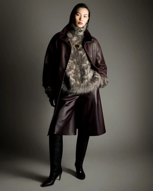 Model Bingbing Liu wearing a burgundy leather coat over a fuzzy turtleneck and tall black boots against a grey seamless backdrop